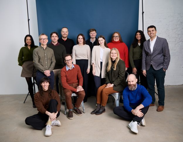 Avencera's team members gather in front of a backdrop in a photo studio.