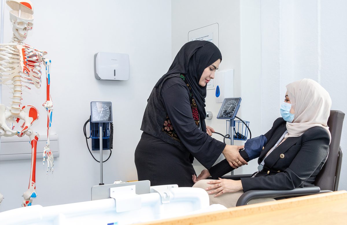 Student uses blood pressure machine on patient