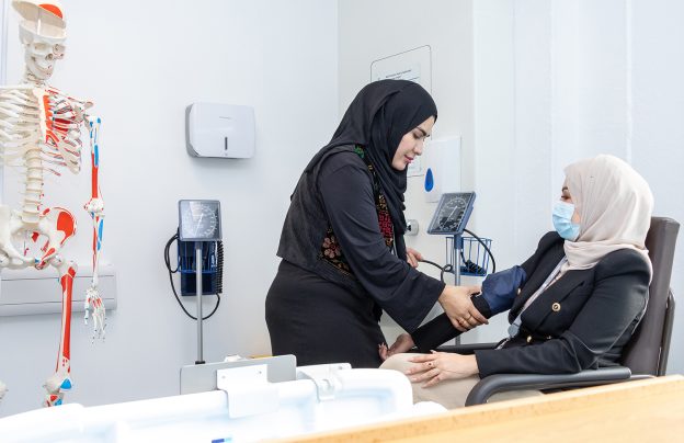 Student uses blood pressure machine on patient