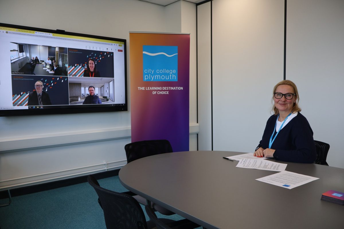 City College Plymouth CEO Jackie Grubb sits at a desk with members of the West College Scotland institution on a screen behind her.