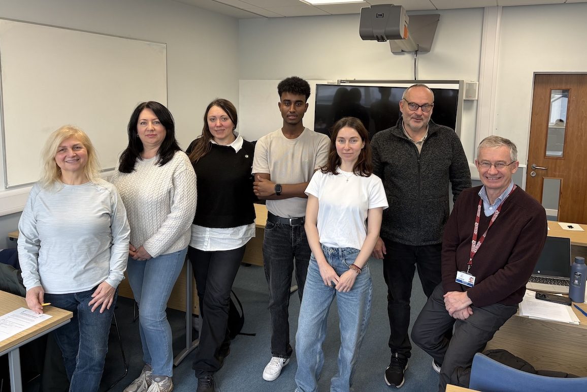 Group of staff and students standing in a classroom setting.