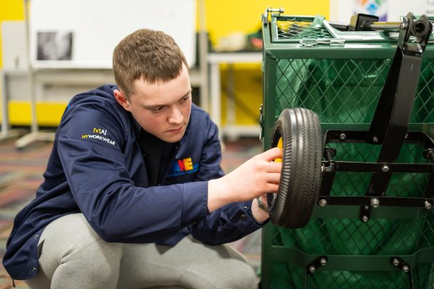 Apprentice fixes wheel on cart