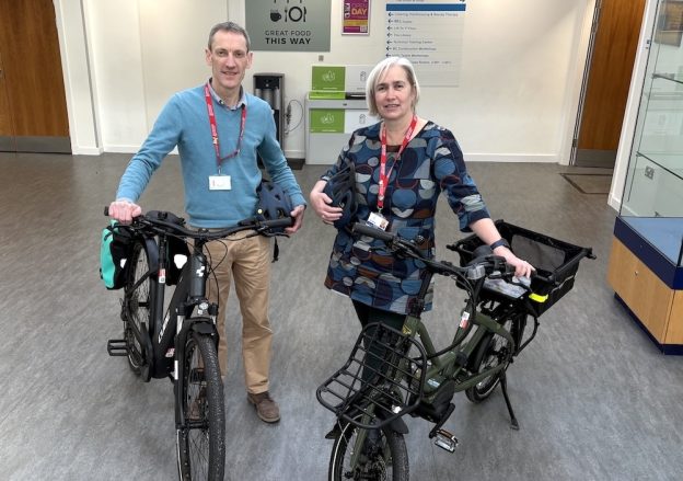 Two people standing at Borders College reception alongside two e-bikes