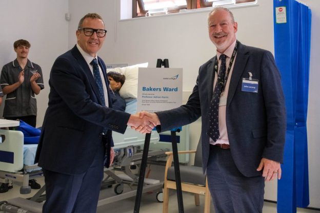 Two people shake hands infront of a plaque unveiling in Exeter College's hospital training ward.