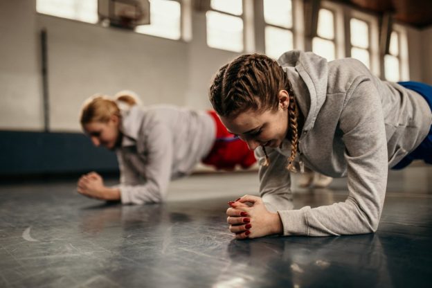 Two learners planking in a gym setting