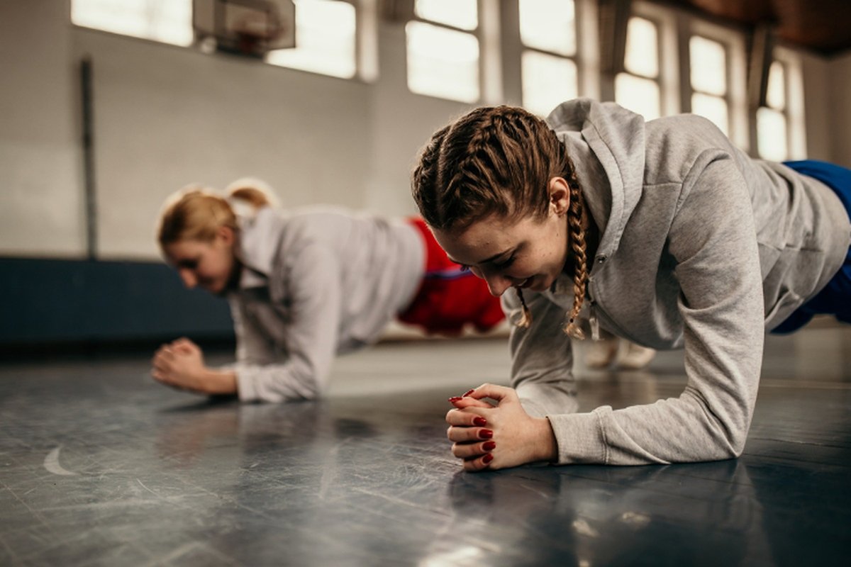 Two learners planking in a gym setting