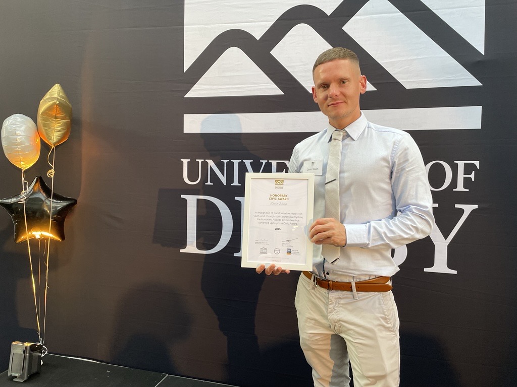 a man collects a civic award from the university of derby