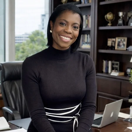 Photo of Olawunmi Brigue, a young black woman with short bobbed hair. She is smiling in the photo and wearing a smart black dress.