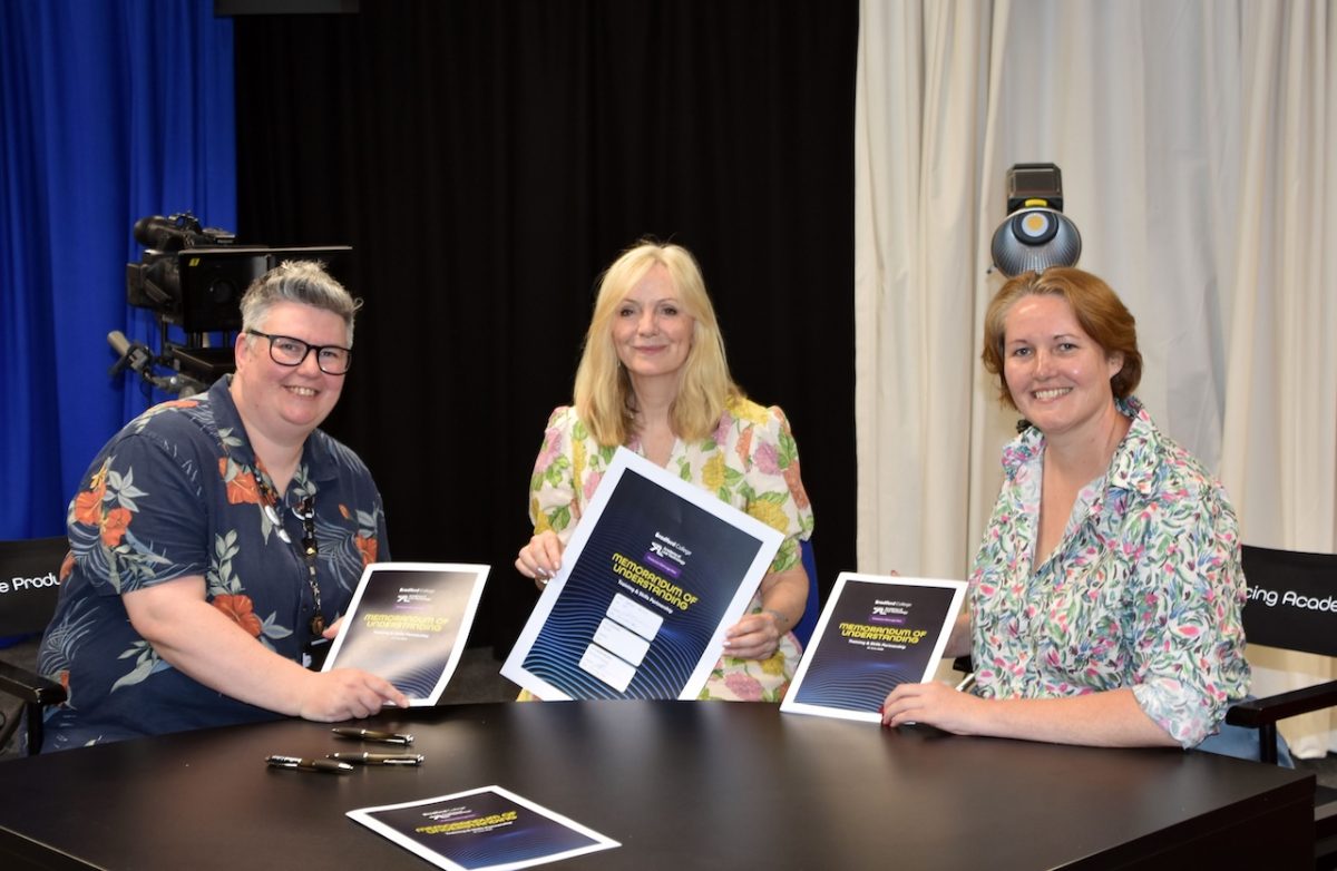 Mayor of West Yorkshire Tracy Brabin (centre) joins representatives from Bradford College (left) and the Academy of Live Technology (right) for the signing of a new Memorandum of Understanding. The three women hold the signed paperwork as they pose together while sat behind a large desk.