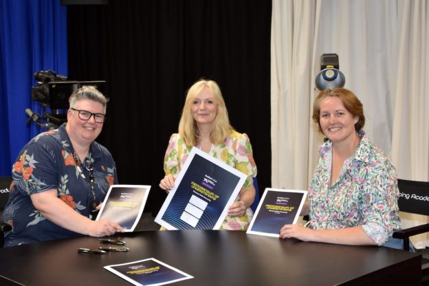 Mayor of West Yorkshire Tracy Brabin (centre) joins representatives from Bradford College (left) and the Academy of Live Technology (right) for the signing of a new Memorandum of Understanding. The three women hold the signed paperwork as they pose together while sat behind a large desk.