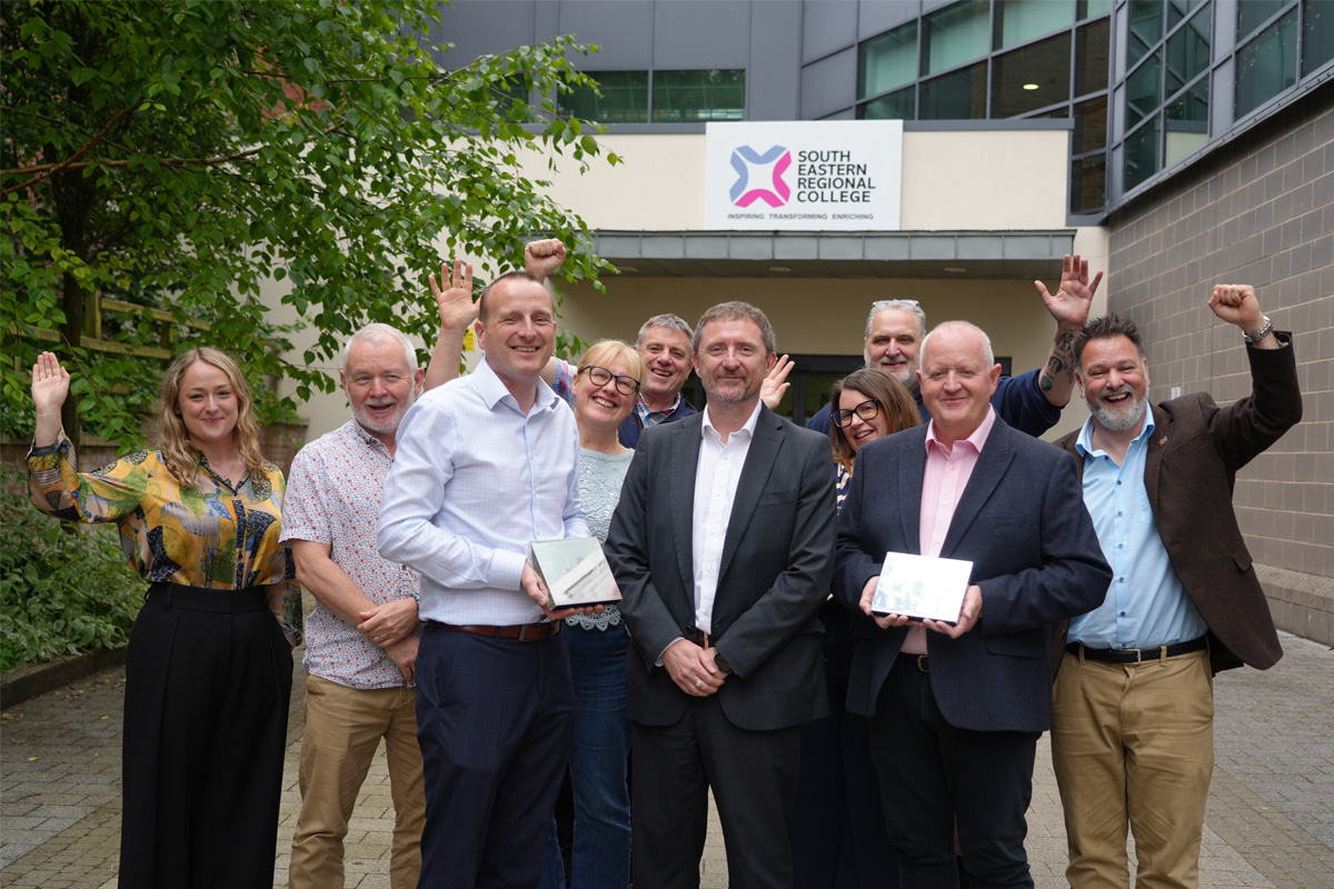 Group of male and female lecturers outside college holding Awards and cheering.