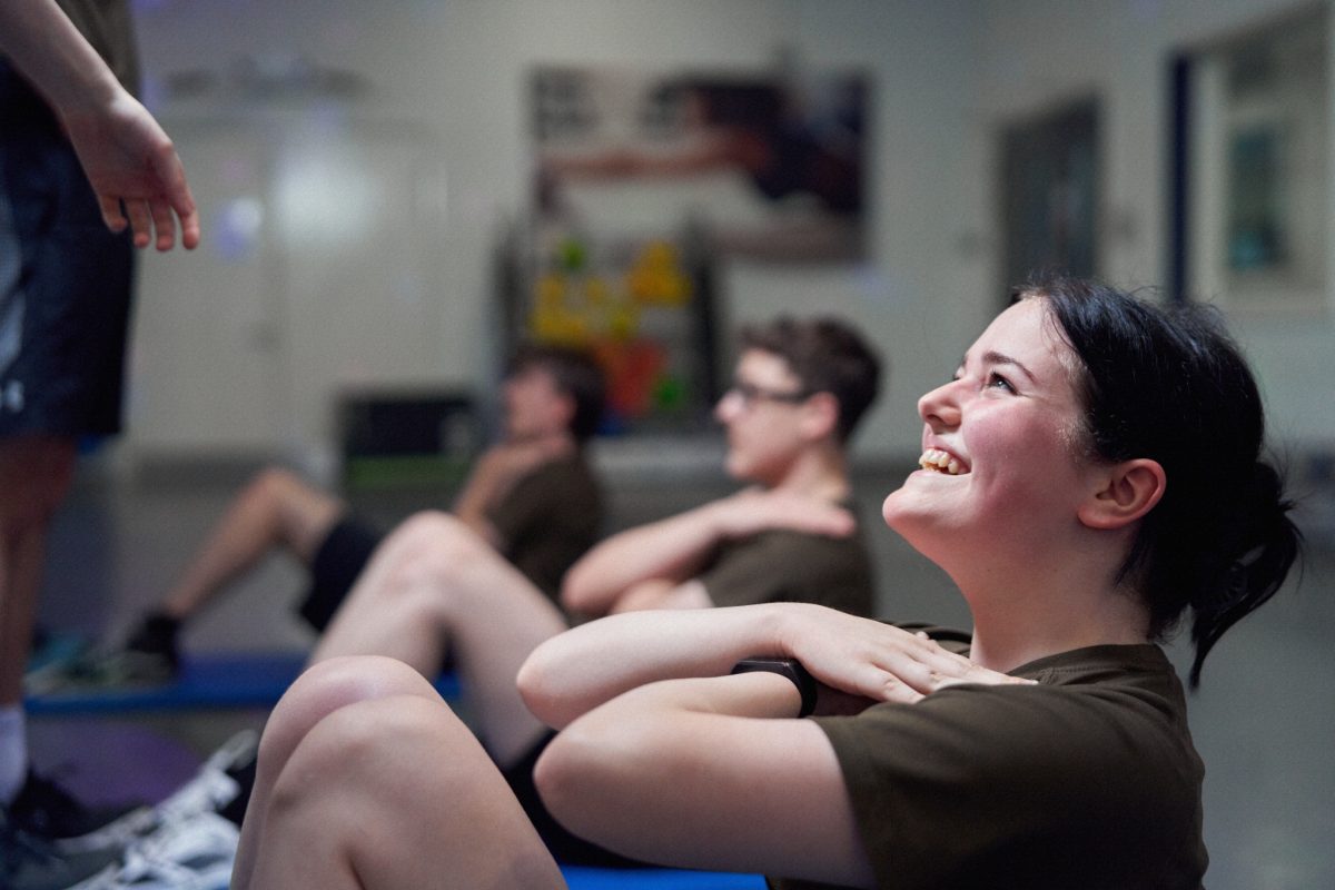 Close up of a young woman doing a sit up with a smile on her face