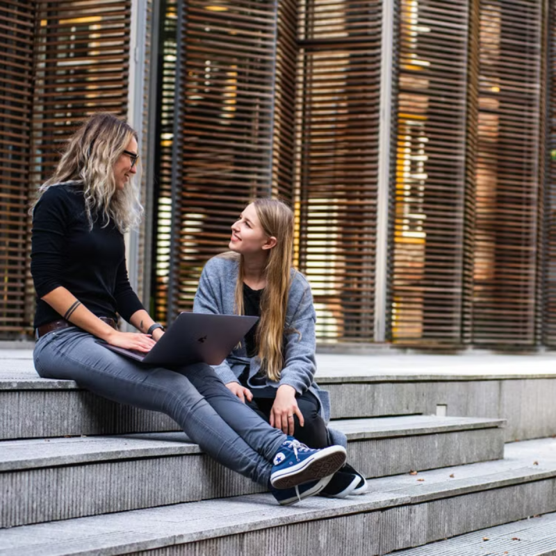student and tutor sat next to each other on stairs