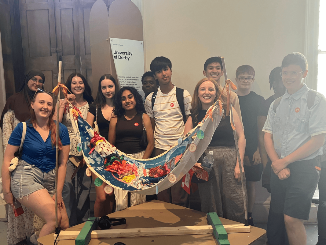 young people are standing round an art exhibition and smiling