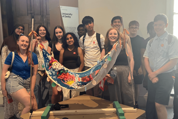 young people are standing round an art exhibition and smiling