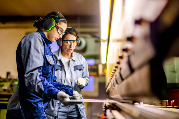 2 women working on a metal cutter