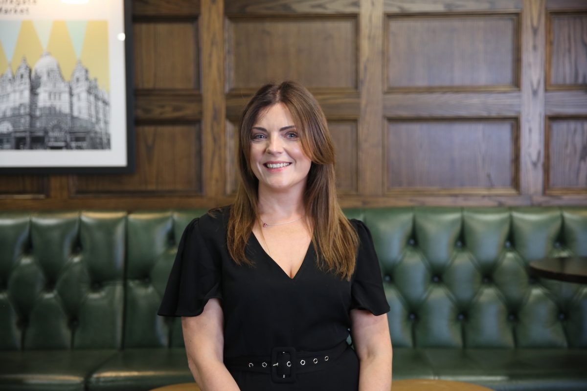 Natalie Dodds, Leeds College of Building’s new Director of CTEC (Construction Technical Excellence Colleges) sits on a padded green leather bench in a room with traditional wooden cladding behind her.