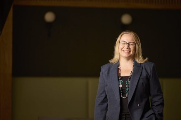 Nikki Davis, Leeds College of Building Principal & CEO, smiles at the camera while standing against a dark backdrop.